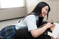 Student on her knees in uniform long hair smiling as she unbuttons students trousers