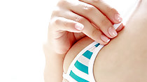 Hand on strap of bikini top barely covering her nipple