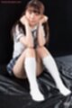 Seated with knees drawn up holding pigtails wearing socks